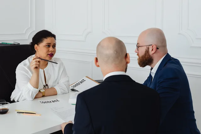 Business colleagues meeting in an office to discuss a contract negotiation. Kontraktpunkter med bureauer: leverance, rettigheder og ophør