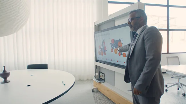 Professional in suit presenting data on screen in a modern office environment. Platformvalg til annoncering: kriterier for danske annoncører